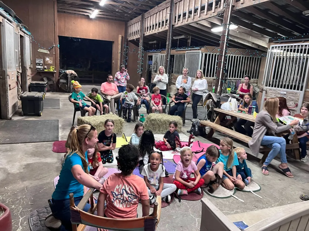A group of children gathered with a horse at the barn